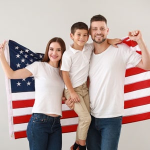 A joyful family proudly holds the American flag, symbolizing the family's immigration to the US - Driggs Immigration Law